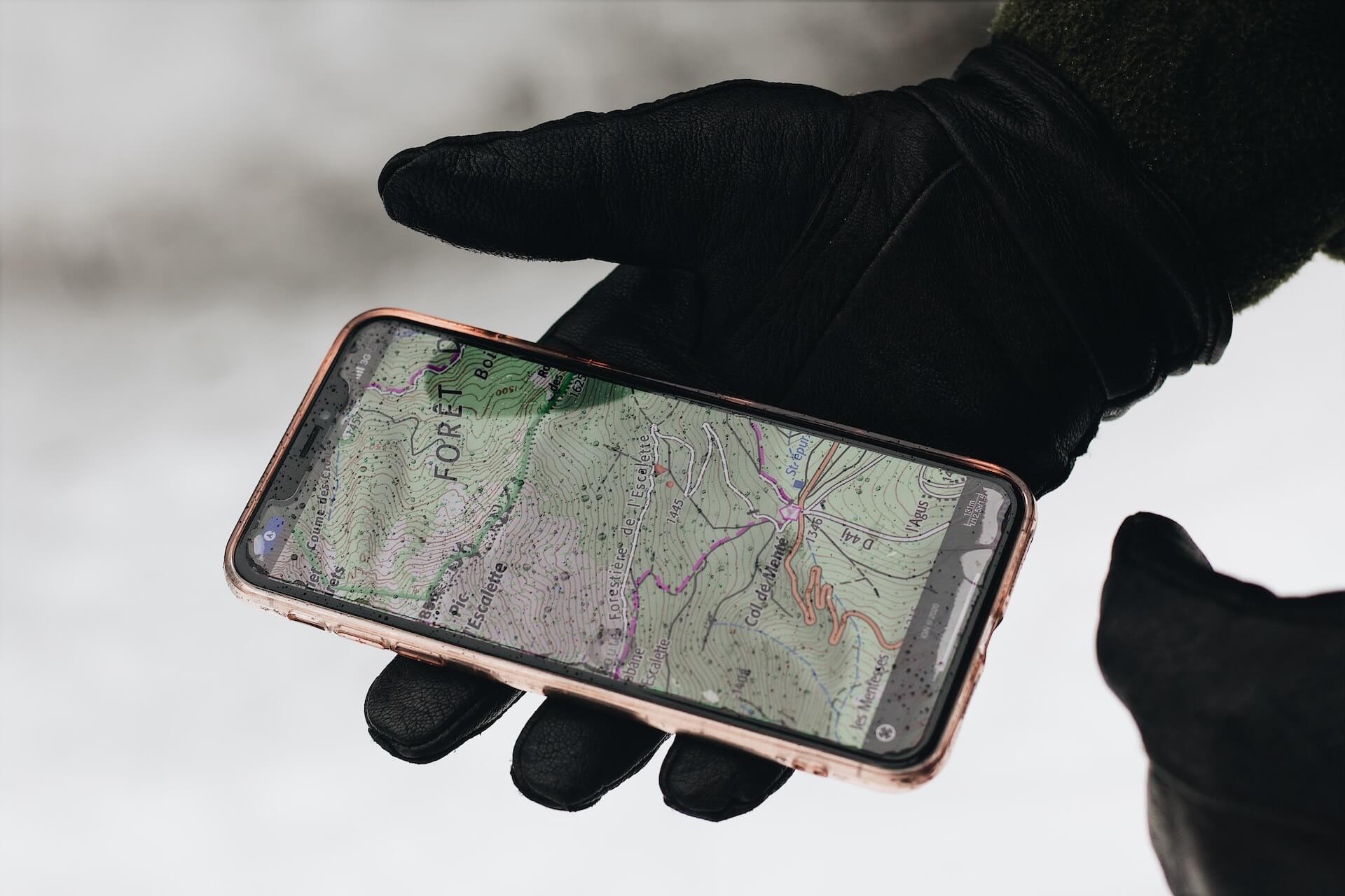 Una persona en la nieve con un smartphone que muestra el mapa GPS.
